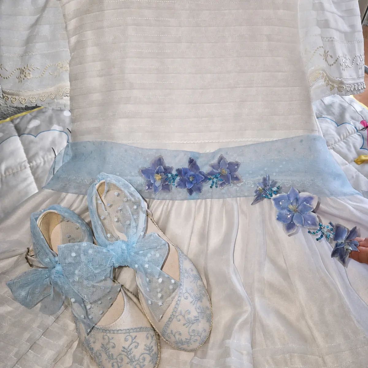 Cinturón artesanal para vestido de comunión confeccionado con flores preservadas de hortensia en tono azul cielo.