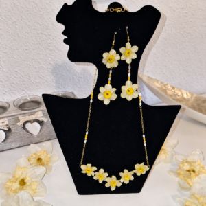 Conjunto Yara de collar gargantilla con cascada de cinco narcisos mini y pendientes colgantes dobles de flores naturales expuestos en un busto de terciopelo negro.