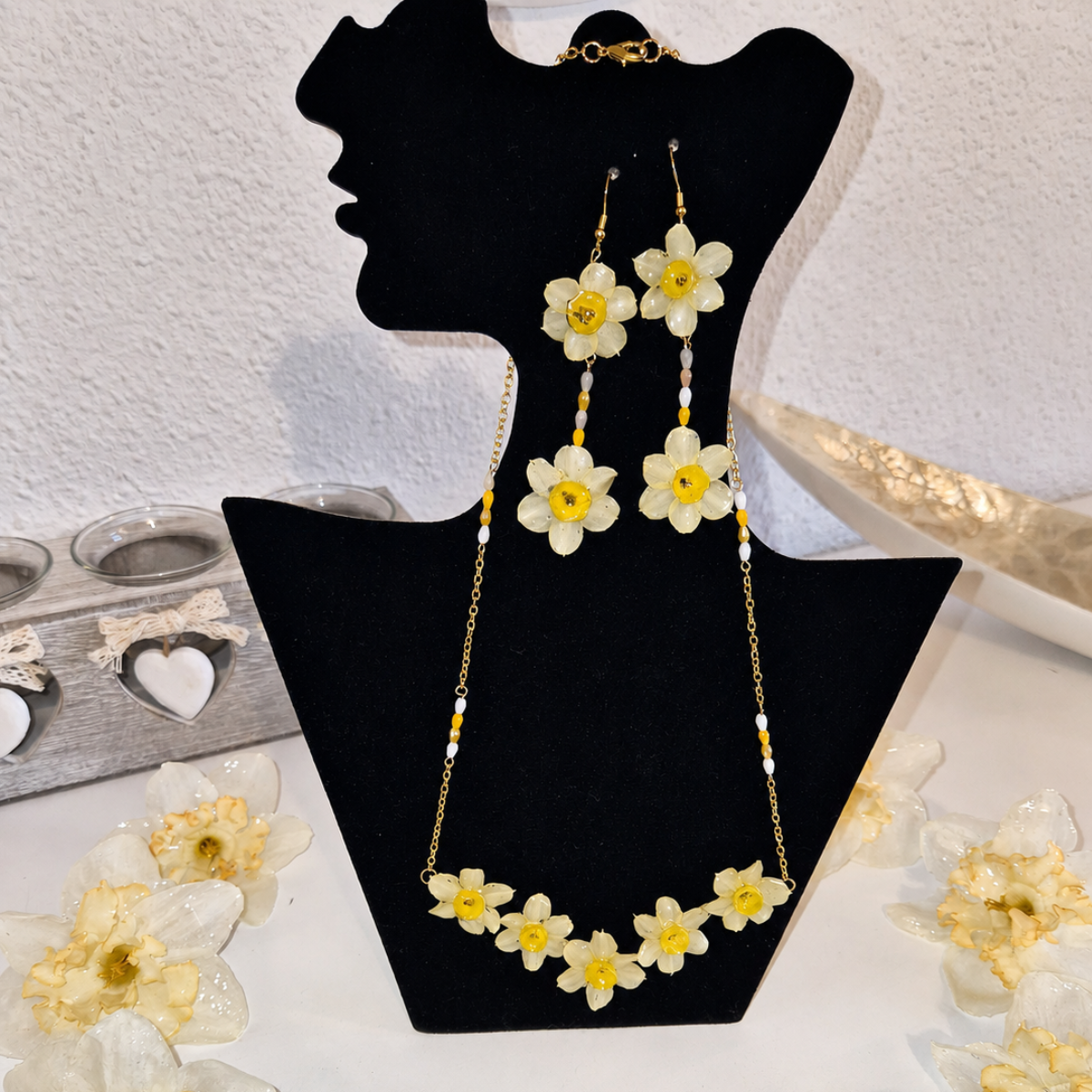 Conjunto Yara de collar gargantilla con cascada de cinco narcisos mini y pendientes colgantes dobles de flores naturales expuestos en un busto de terciopelo negro.