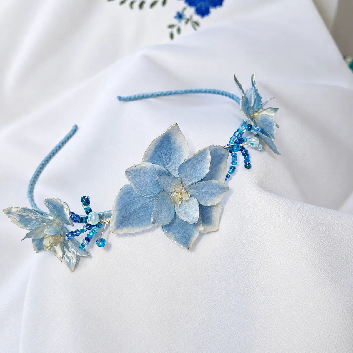 Diadema artesanal de flores naturales de hortensia en tono azul.