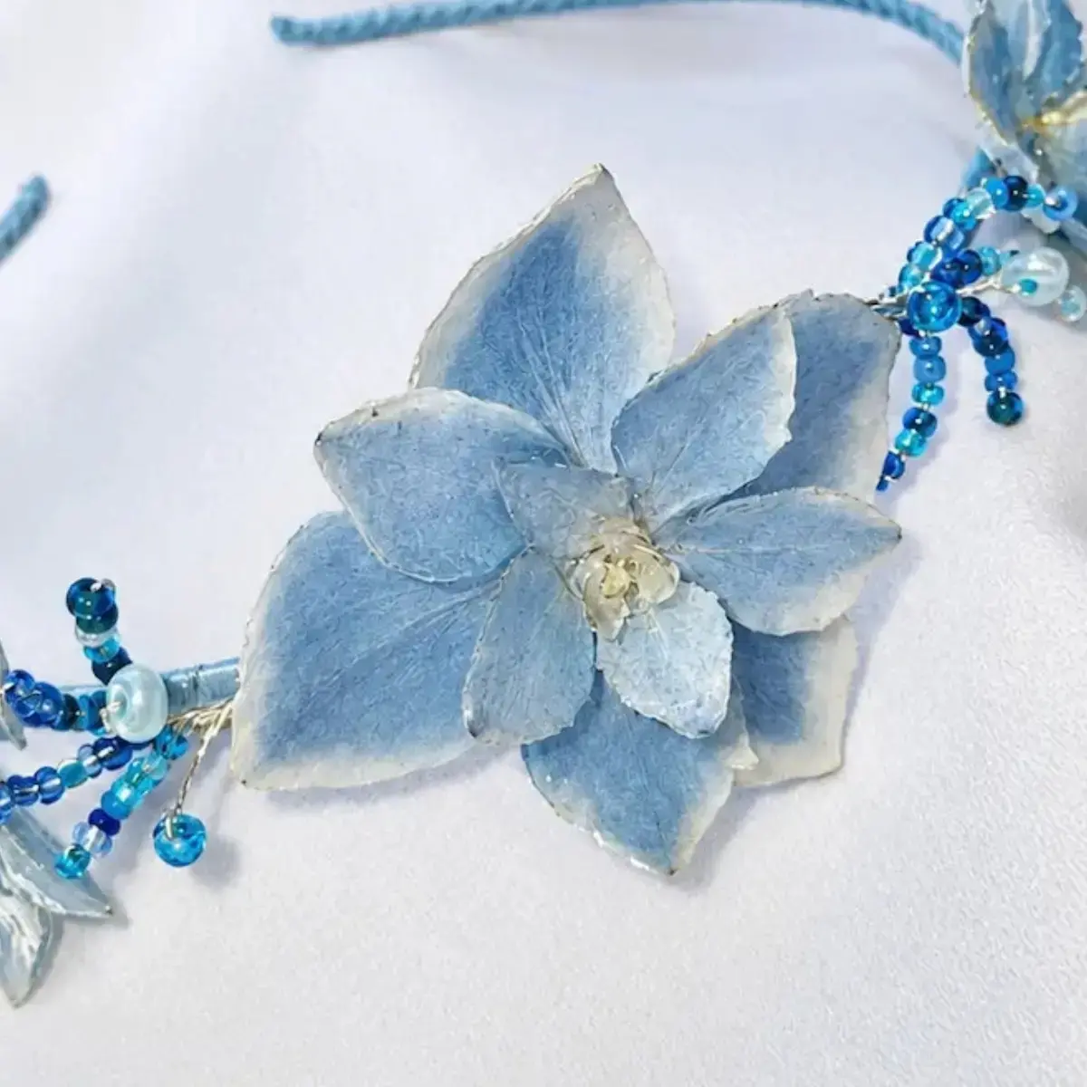 Diadema artesanal de flores naturales de hortensia en tono azul.